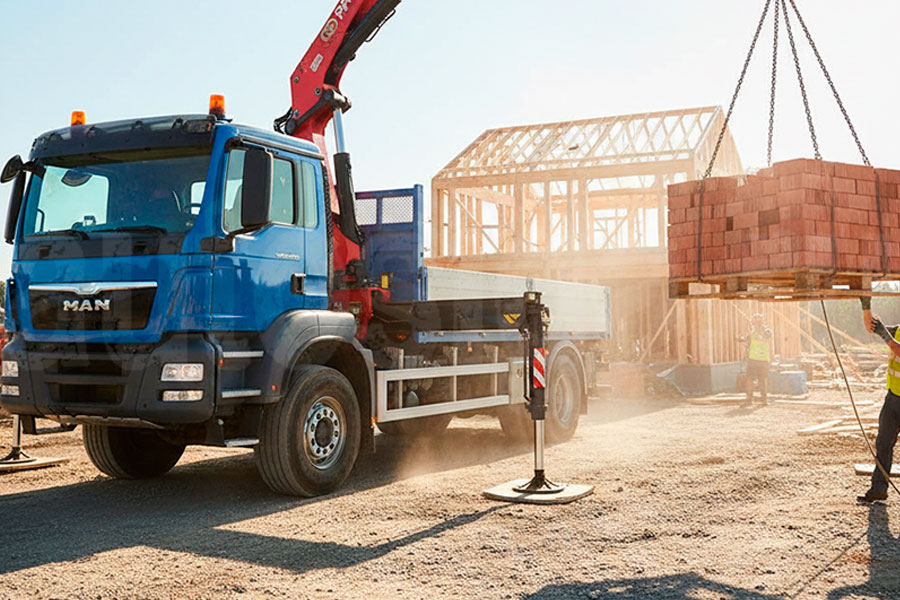 Кран-манипулятор PALFINGER PK 4501 поднимает поддон с кирпичом на стройке