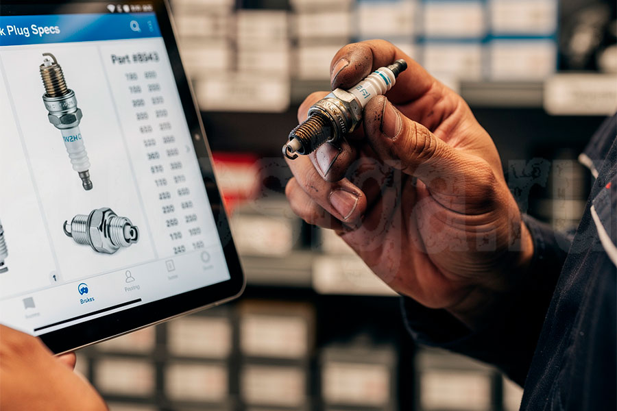 Правильный подбор свечей зажигания для конкретного автомобиля Механик подбирает свечи зажигания по каталогу в магазине автозапчастей