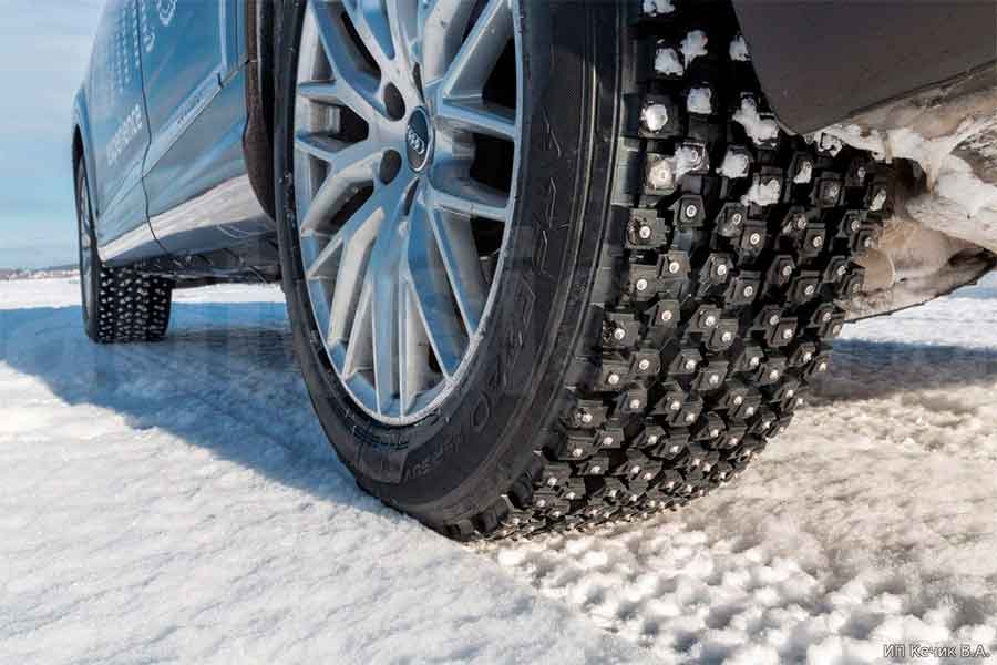 Шипованные зимние шины на автомобиле в снегу зимой