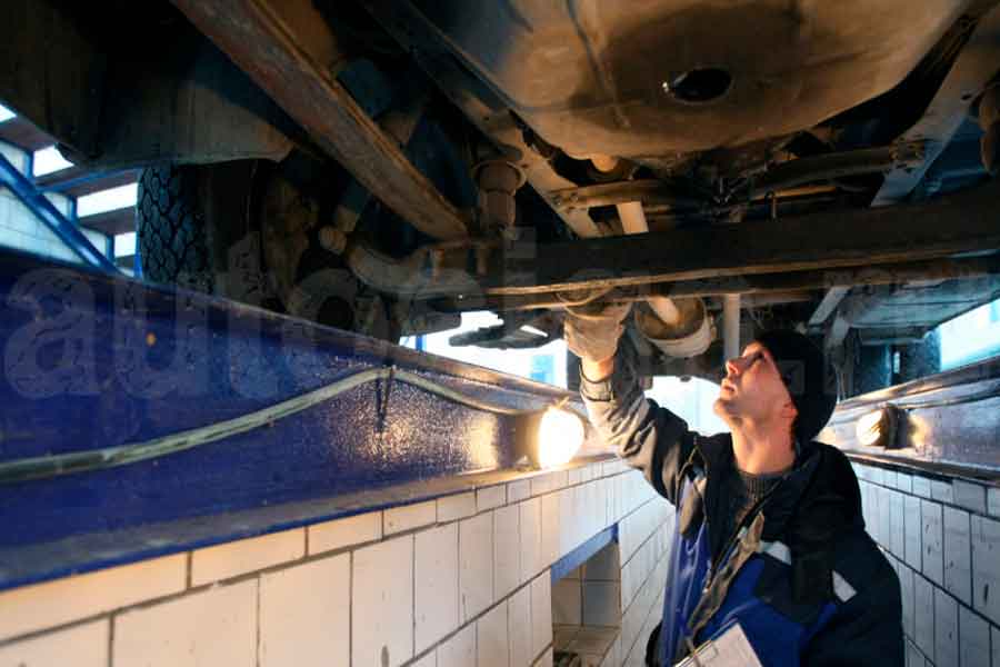 Проверка днища автомобиля перед покупкой: поиск ржавчины, течей и скрытых дефектов Человек осматривает днище автомобиля на предмет ржавчины и повреждений