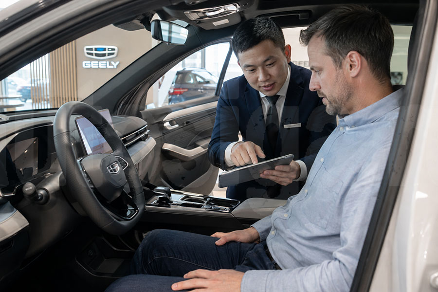 Осмотр комплектации Geely Покупатель осматривает комплектацию нового Geely в автосалоне