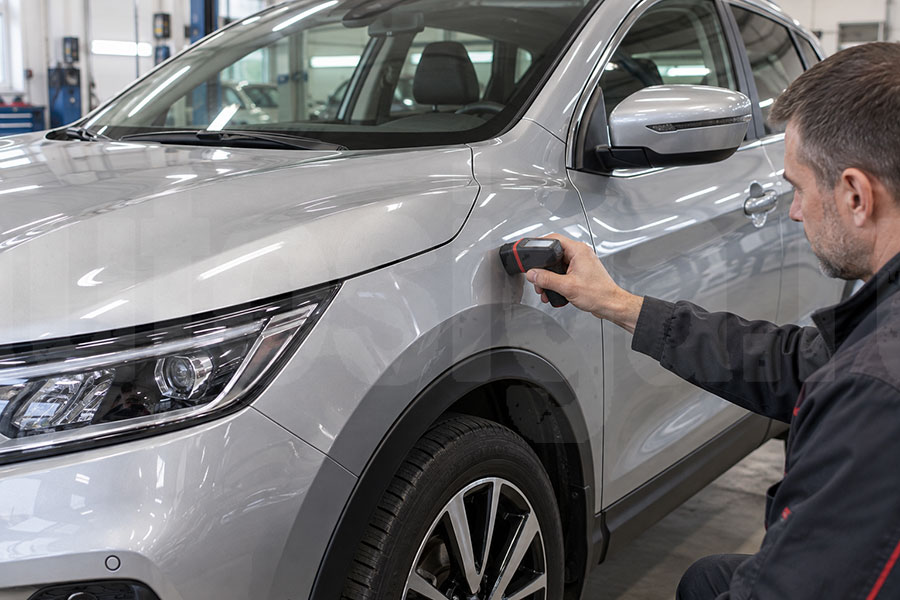 Специалист проверяет толщиномером кузов Nissan Qashqai перед покупкой